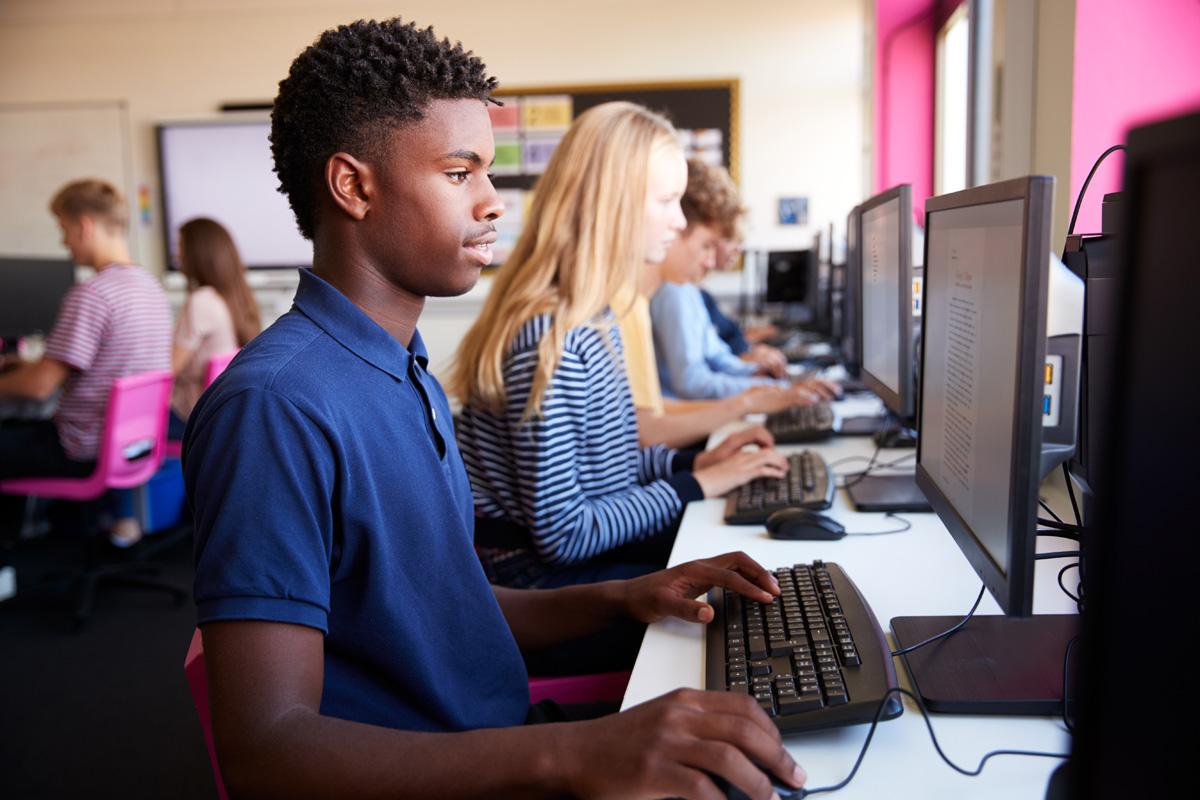 teenage students sitting at a row of computers